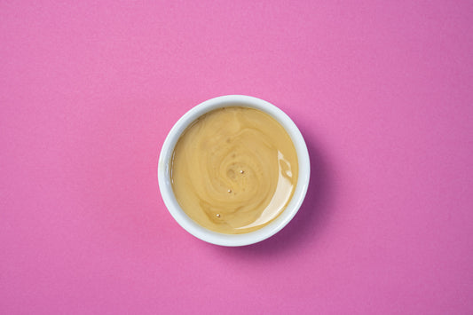 Bowl of creamy peanut butter on a pink background.